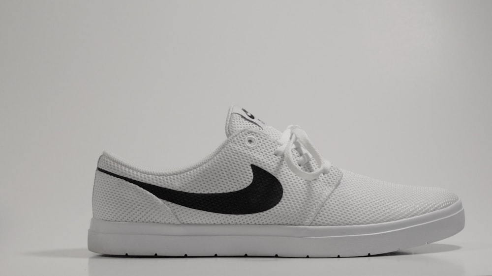 Un zapato Nike blanco y negro sobre una superficie blanca