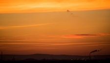 a plane flying in the sky at sunset