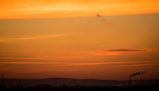 a plane flying in the sky at sunset