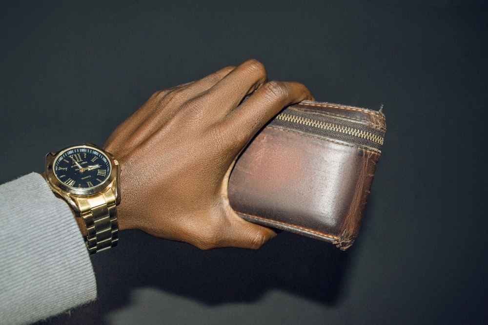 a person holding a wallet and a watch