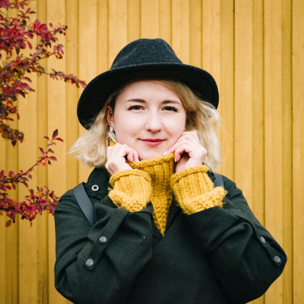 a woman wearing a black hat and yellow mittens