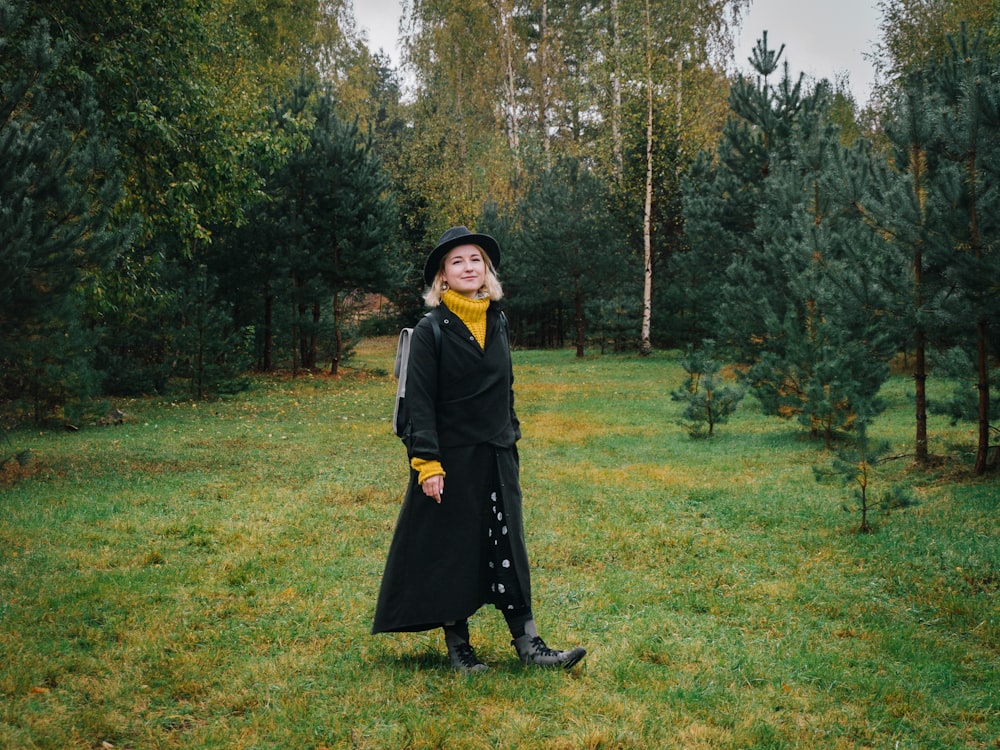 a woman standing in a field with trees in the background
