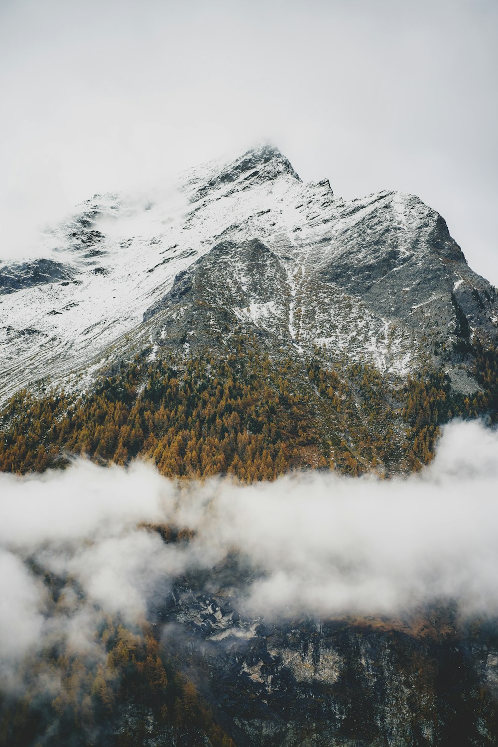 Una montagna coperta di neve e circondata da nuvole