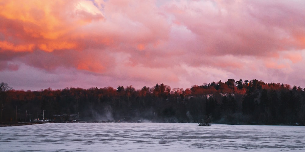 a boat floating on top of a lake under a cloudy sky