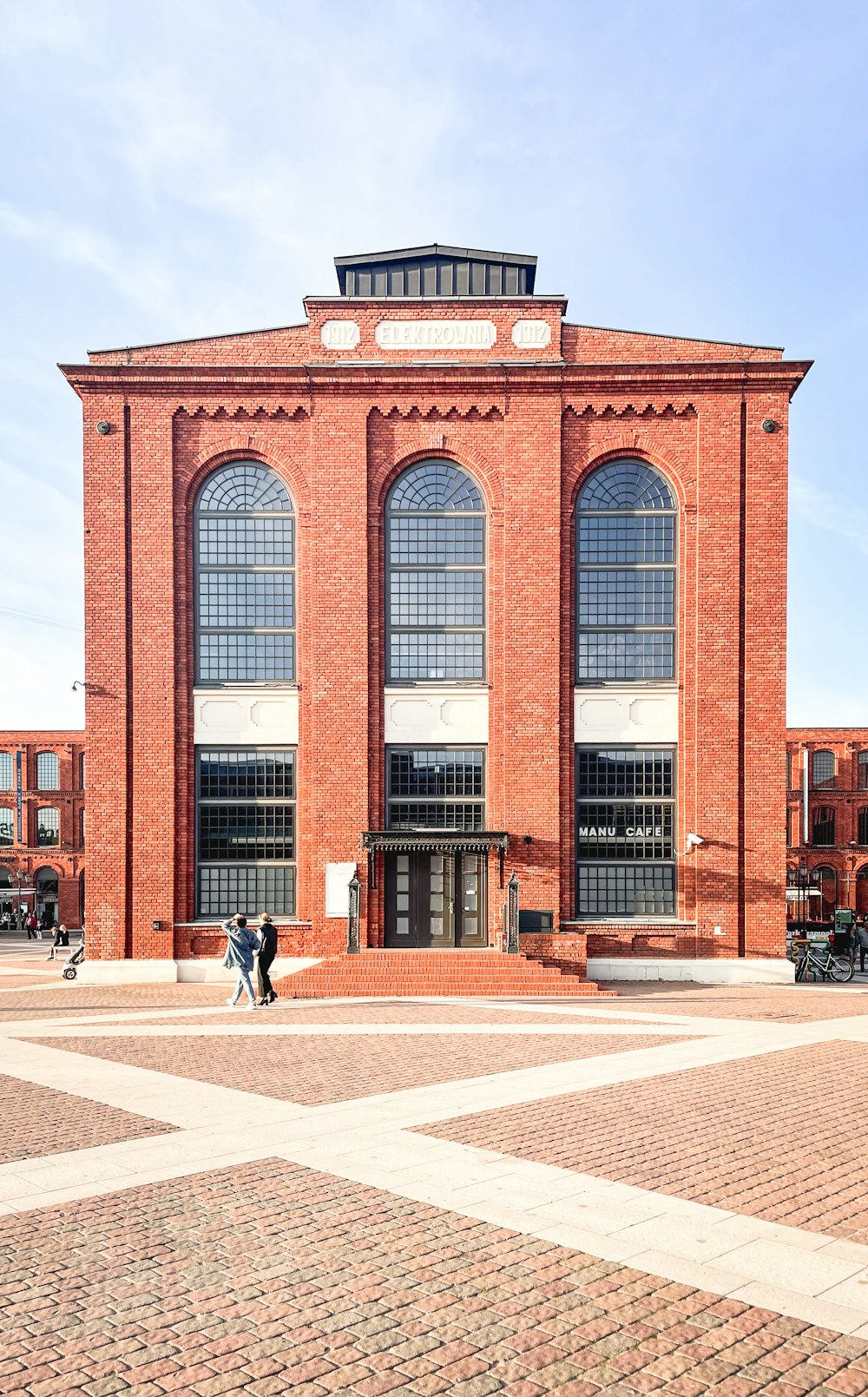 a brick building with two people walking in front of it