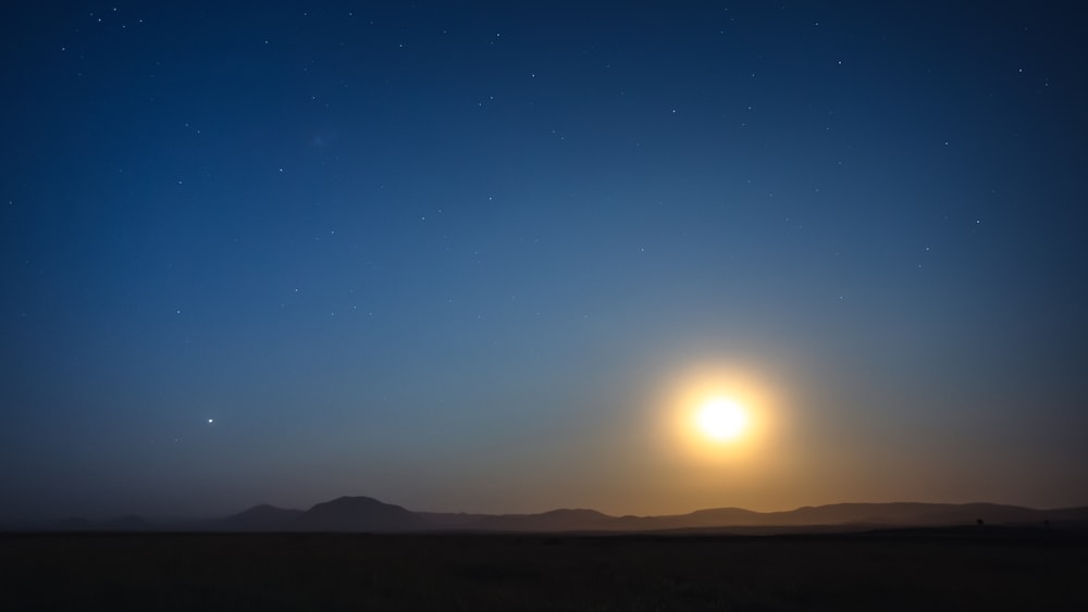 the sun is setting over the mountains in the distance