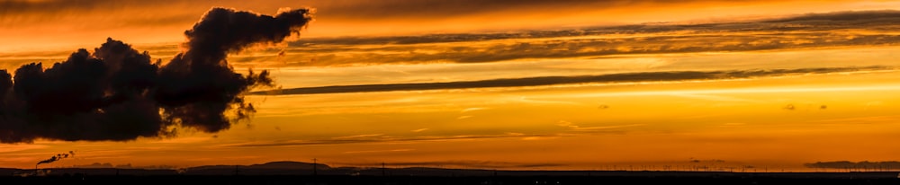 a plane flying in the sky at sunset