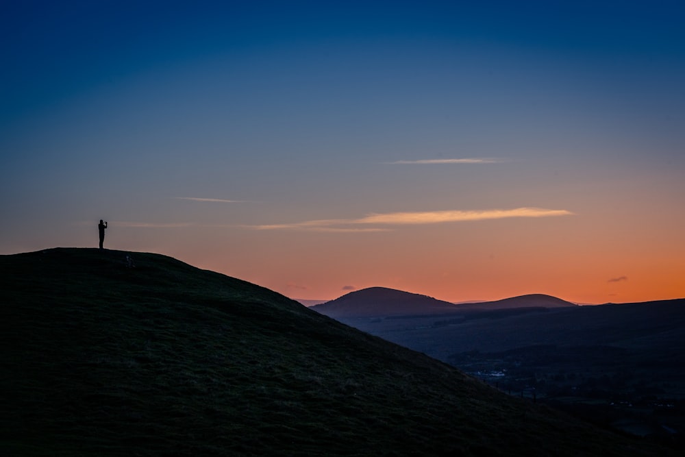 a person standing on top of a hill at sunset