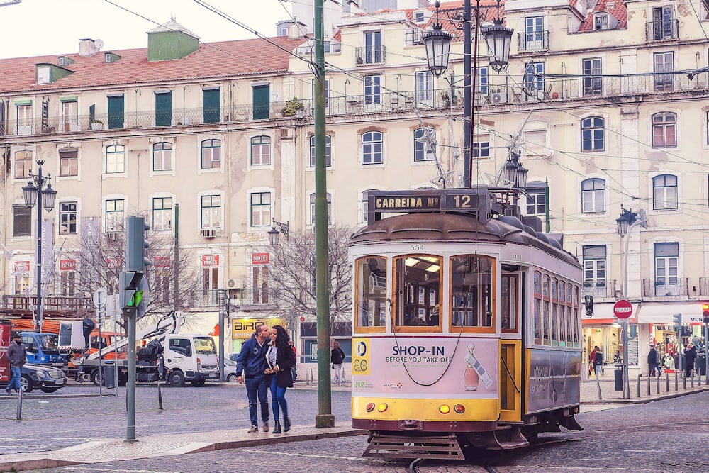 a couple of people standing on a street next to a trolley