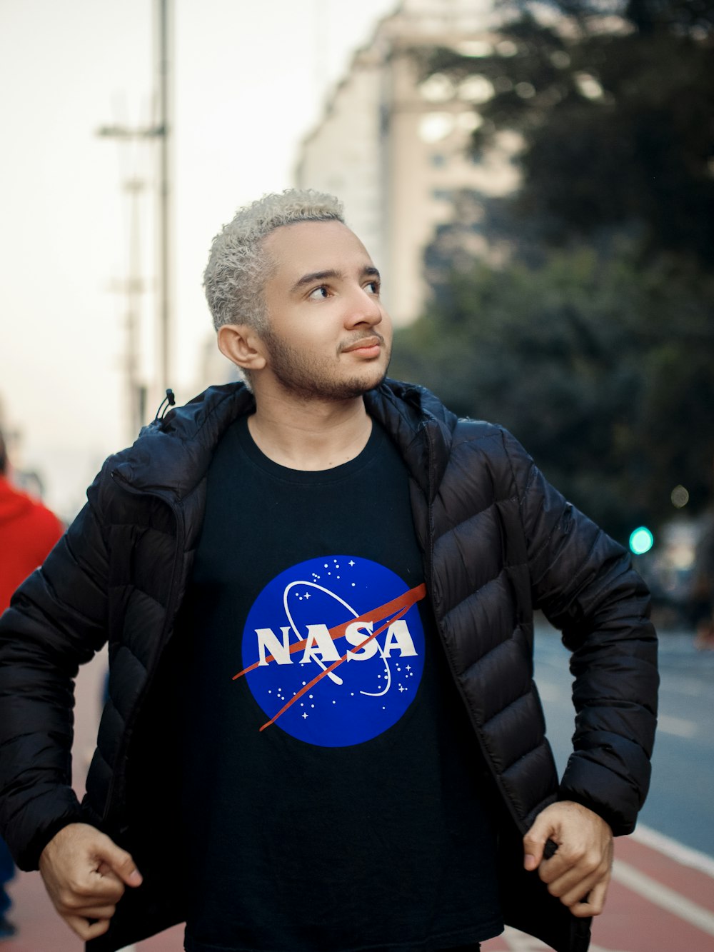 a man in a nasa t - shirt standing on a street