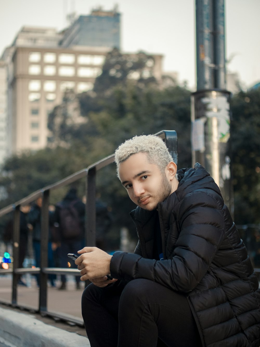 a man sitting on a ledge looking at his cell phone