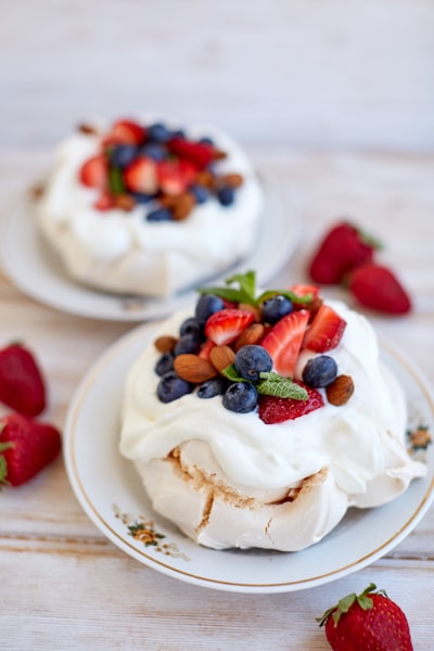 two desserts on a white plate with strawberries and blueberries
