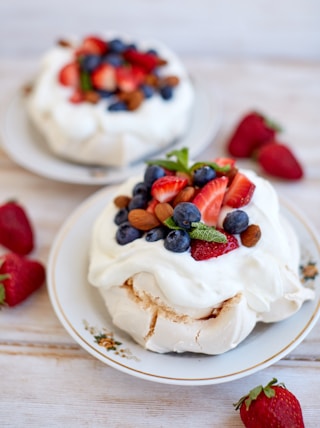 two desserts on a white plate with strawberries and blueberries