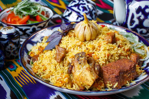 A close-up of a steaming plate of fragrant Yemeni mandi rice with tender lamb, garnished with fresh herbs.