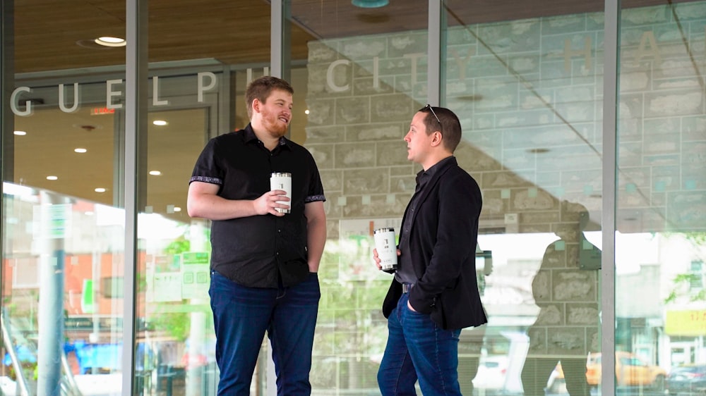 two men standing outside of a building talking