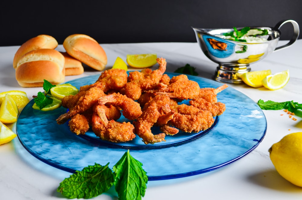 a blue plate topped with fried shrimp next to lemon wedges