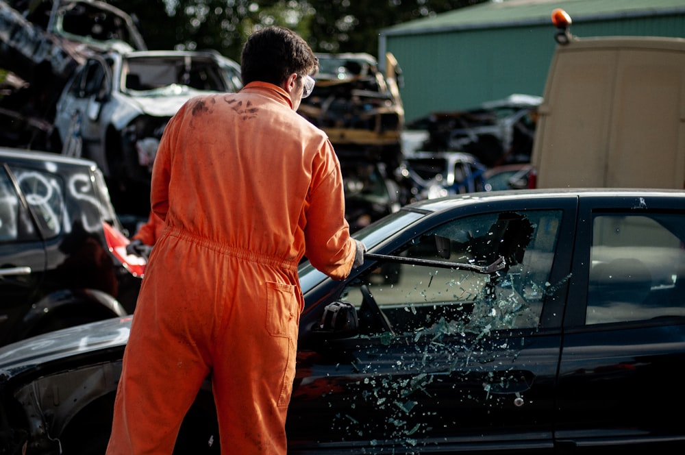 a man in an orange jumpsuit standing next to a car