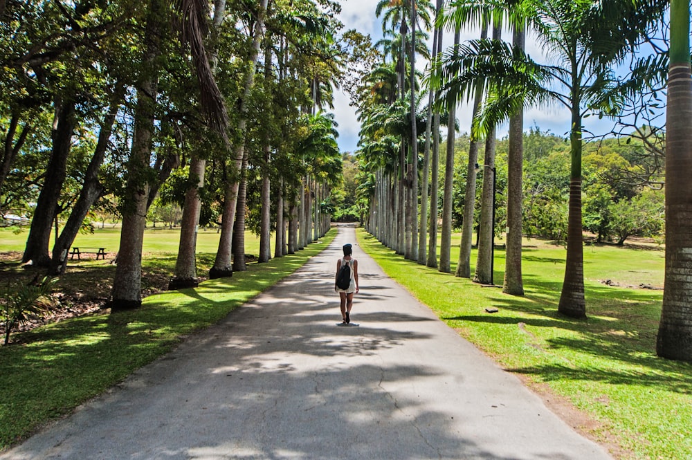 a person riding a skateboard down a tree lined road