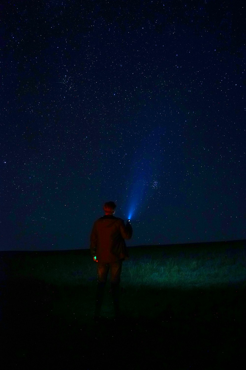 a man standing in a field with a flashlight in his hand