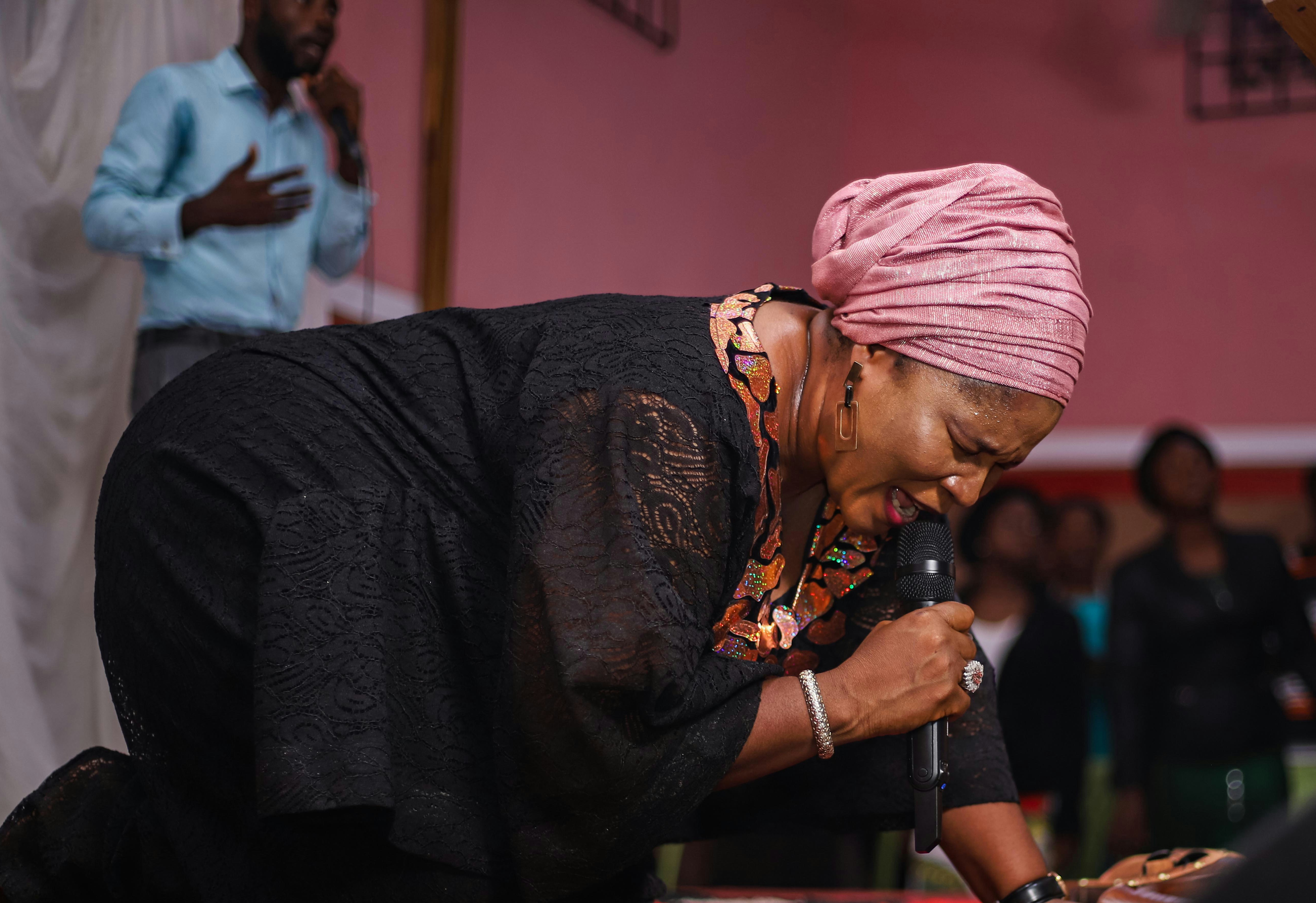a woman in a pink turban is holding a microphone
