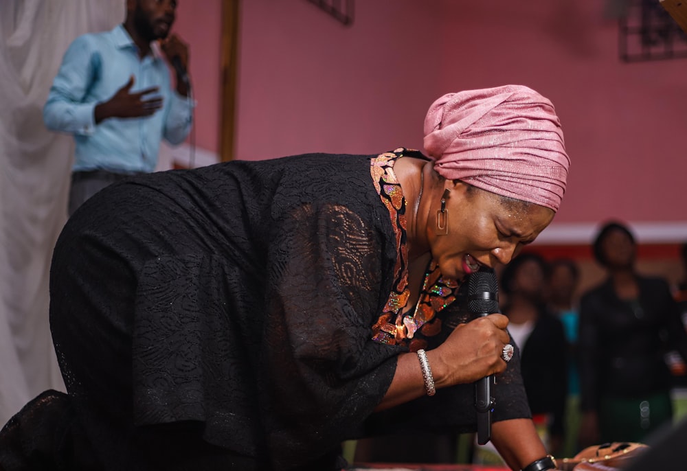 a woman in a pink turban is holding a microphone