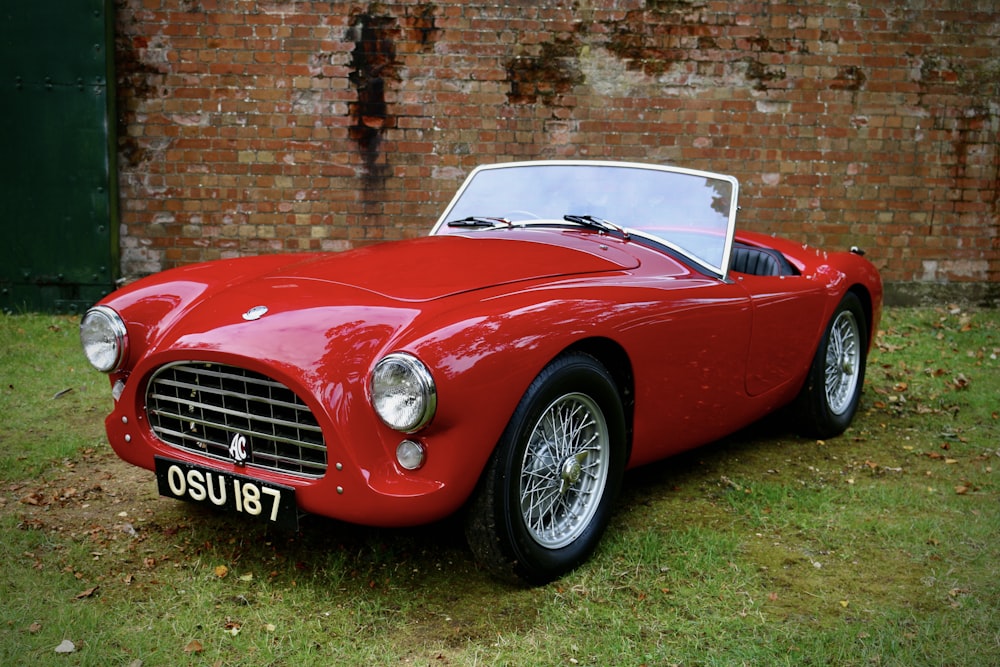 a red sports car parked in front of a brick wall