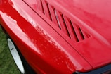 Close-up of a freshly polished red sports car hood reflecting sunlight.