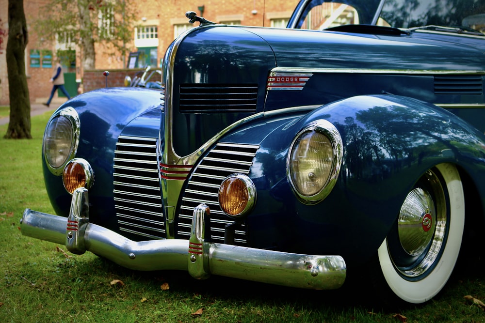 an old blue car parked on top of a lush green field