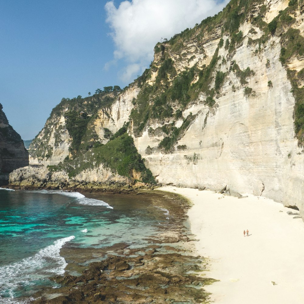 a sandy beach next to a rocky cliff