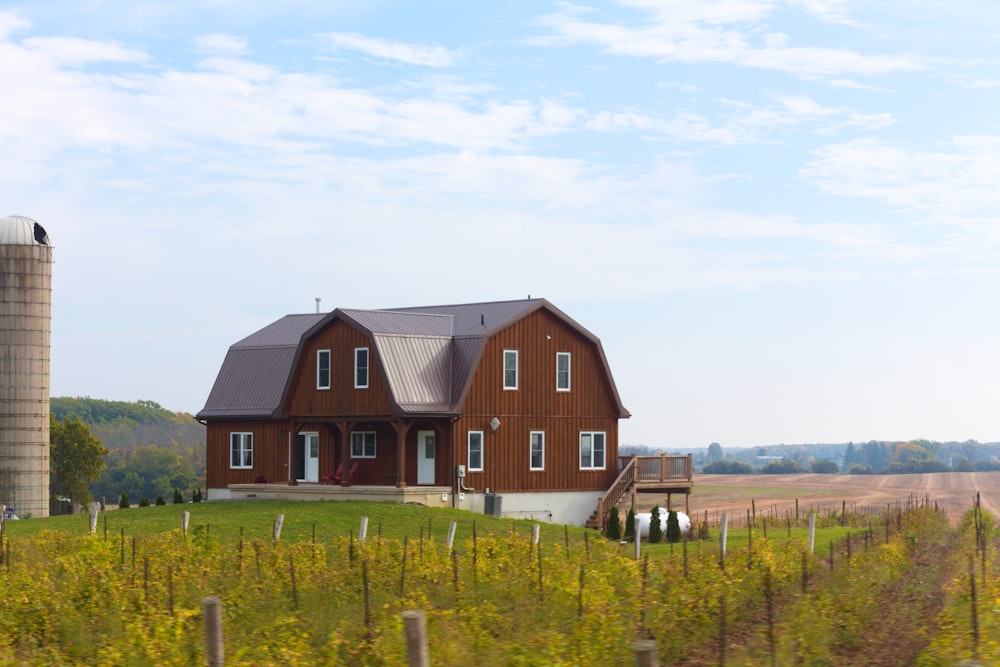 a large brown house sitting on top of a lush green field