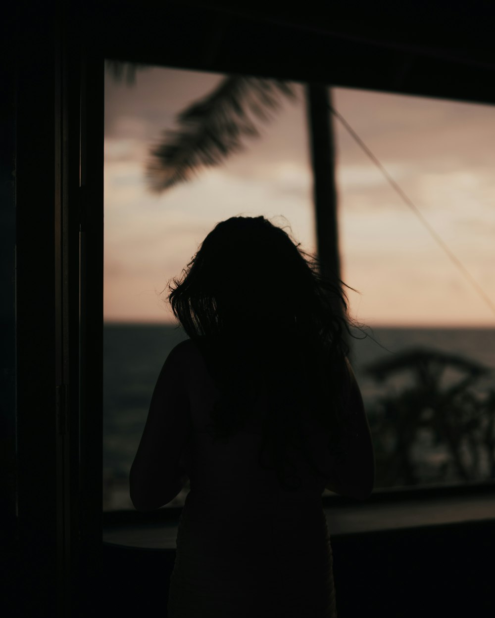 a woman looking out a window at the ocean