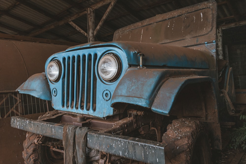 an old blue jeep is parked in a garage