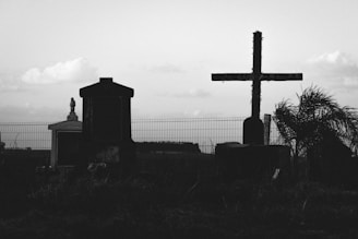a black and white photo of a cemetery with a cross