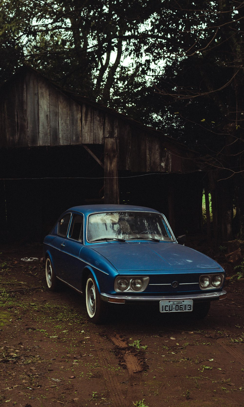 Ein blaues Auto, das vor einer Holzkonstruktion geparkt ist