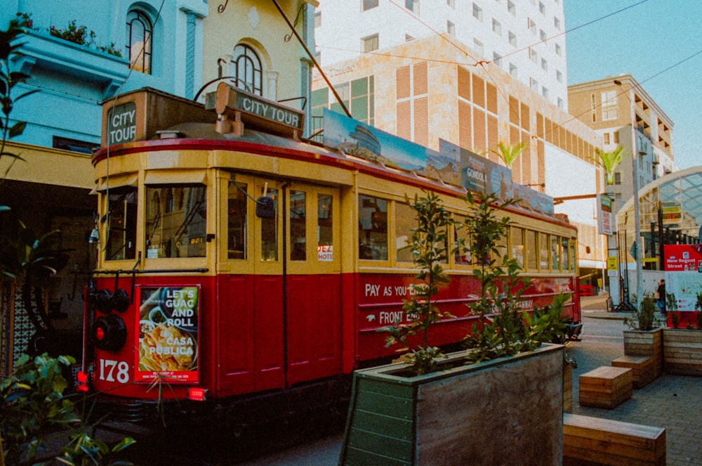 a red and yellow trolley car on a city street
