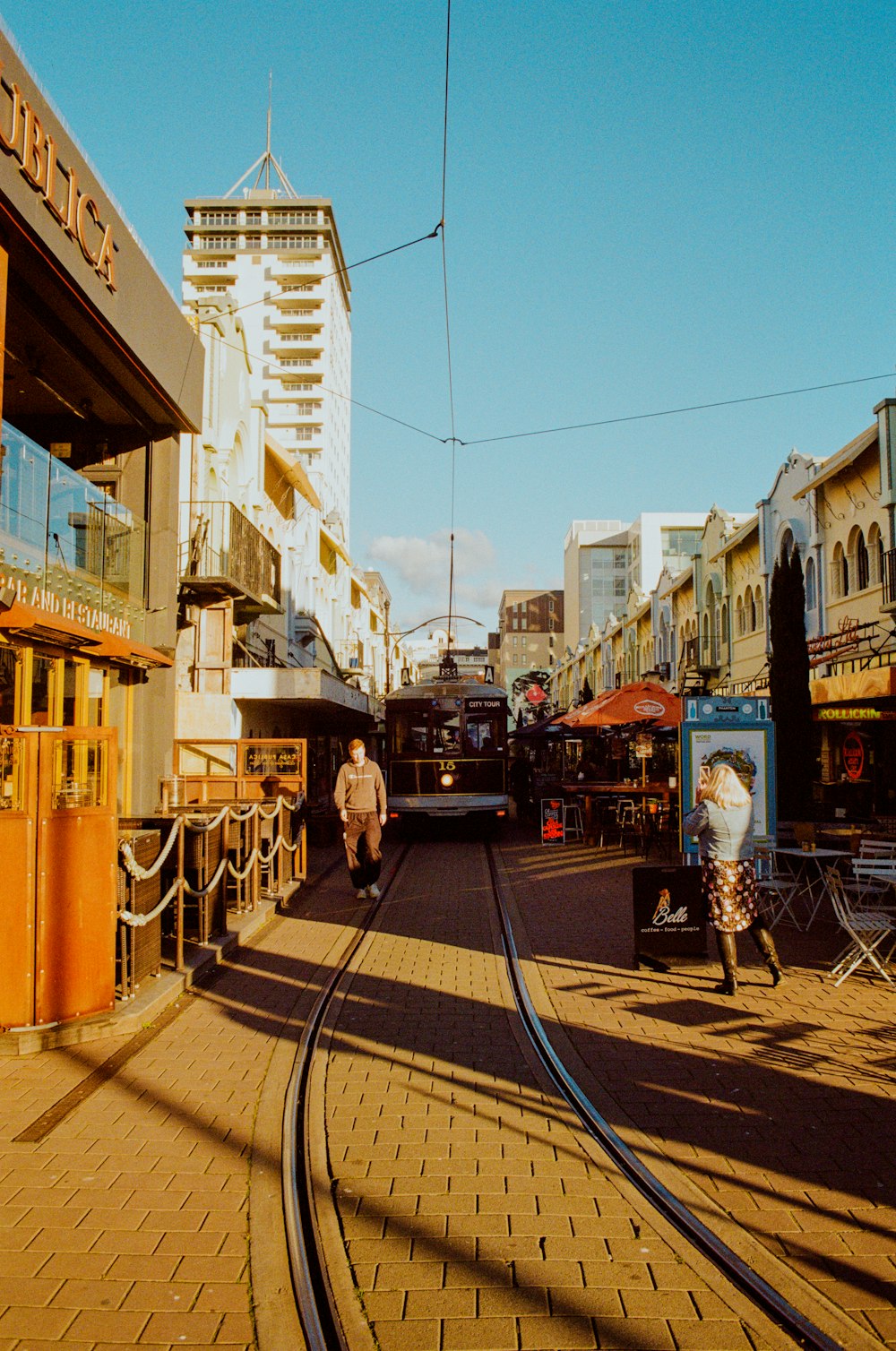 a man walking down a street next to a train track