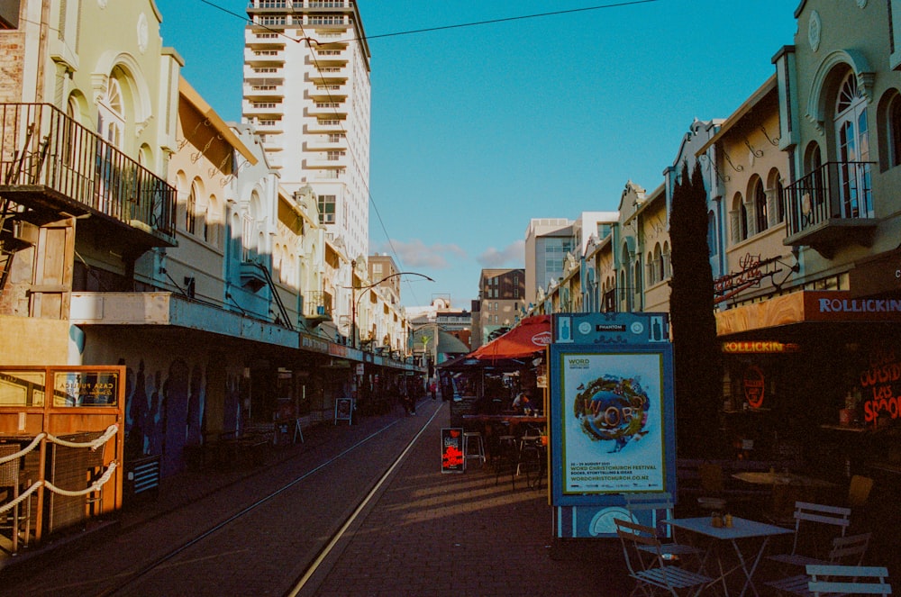 a city street with buildings and tables and chairs