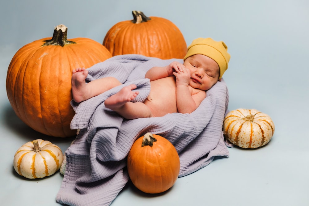 a baby wrapped in a blanket surrounded by pumpkins