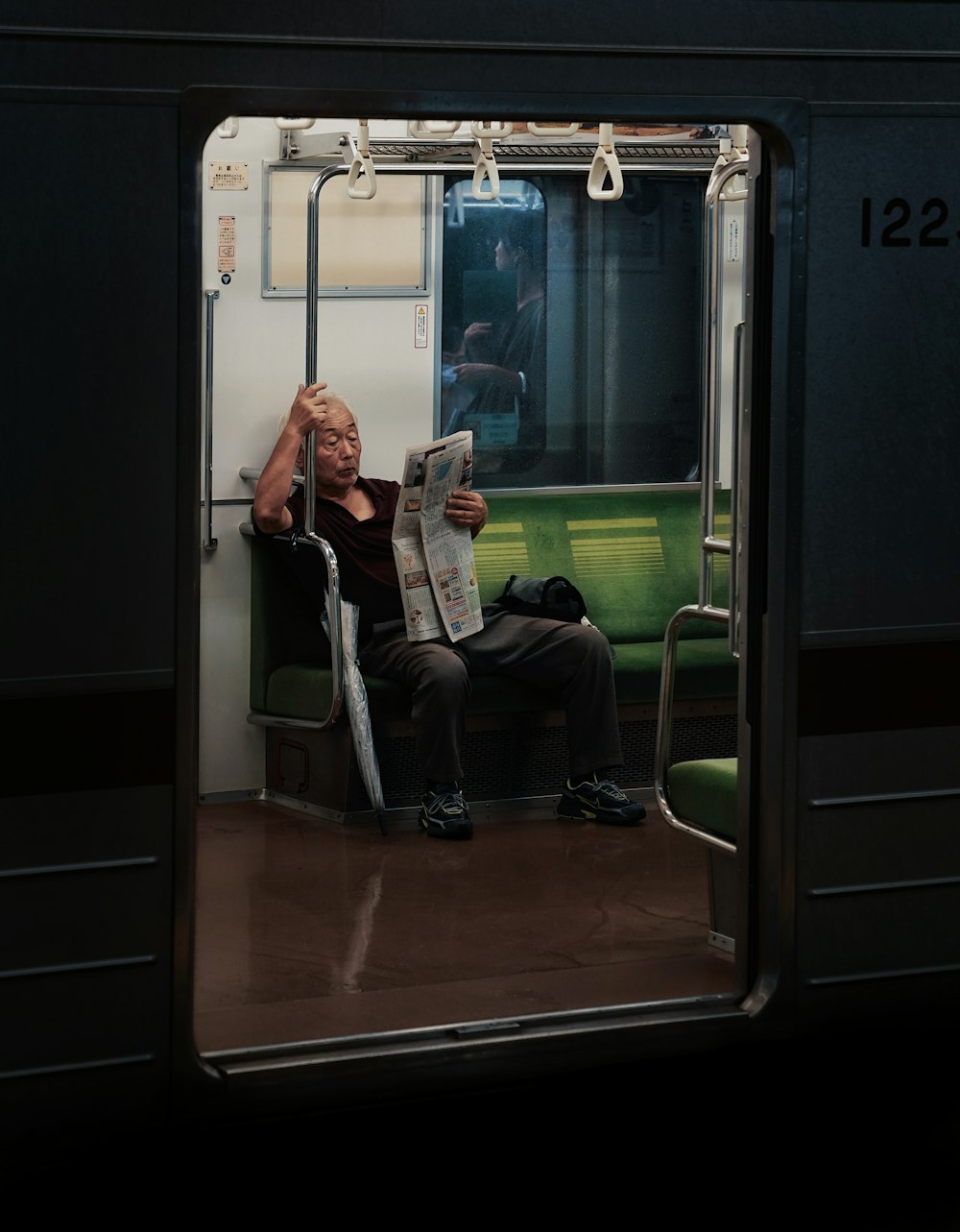 a man sitting on a train reading a newspaper