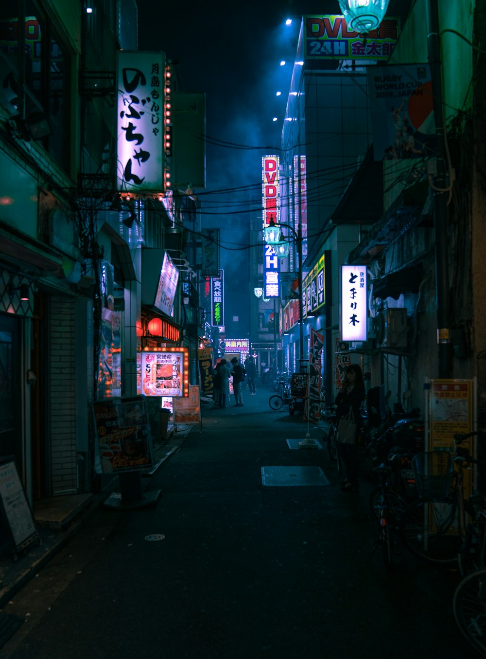 a narrow city street at night with neon signs