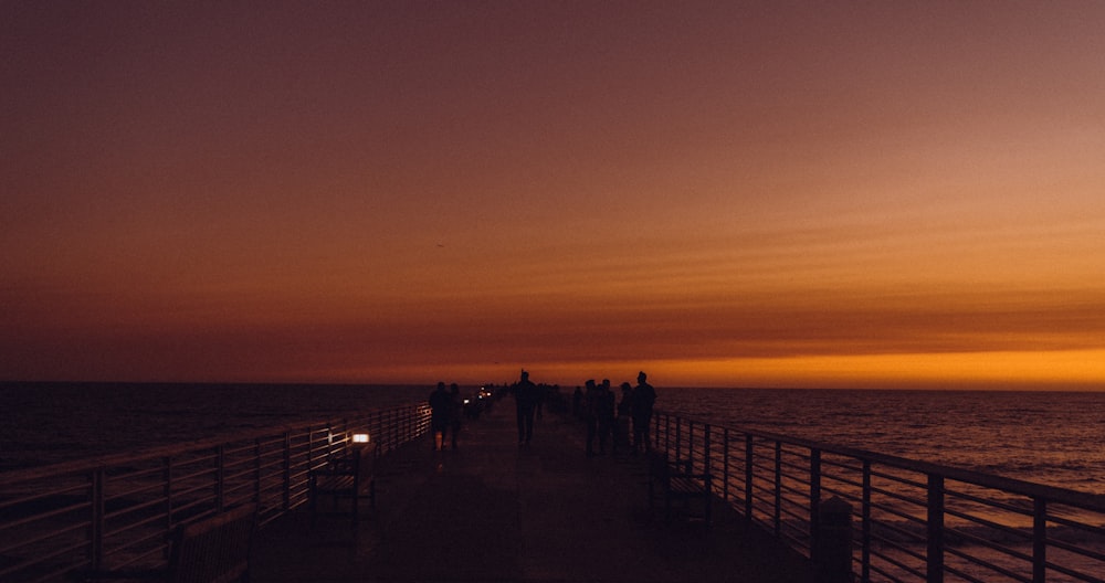 a group of people standing on a pier next to the ocean