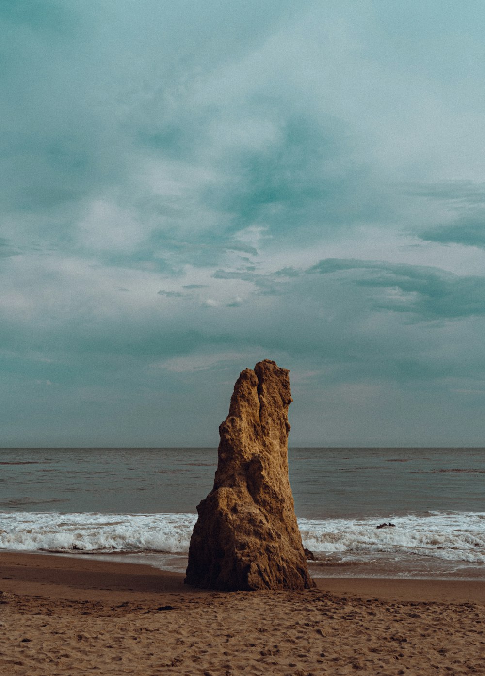 a large rock sitting on top of a sandy beach