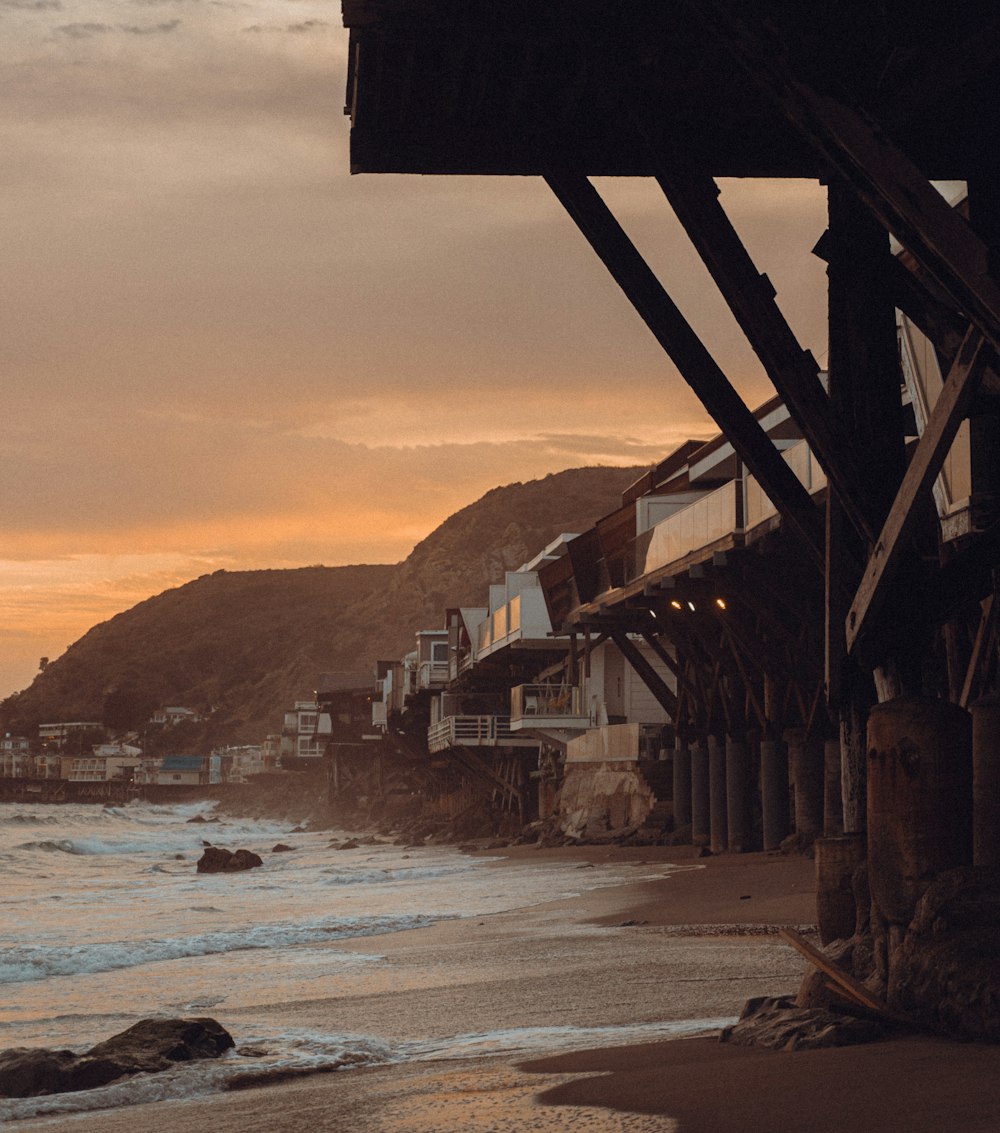 a view of a beach at sunset with houses in the background