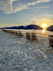 A cozy Oak Island beach scene with colorful umbrellas and chairs set up near the shore at sunset.
