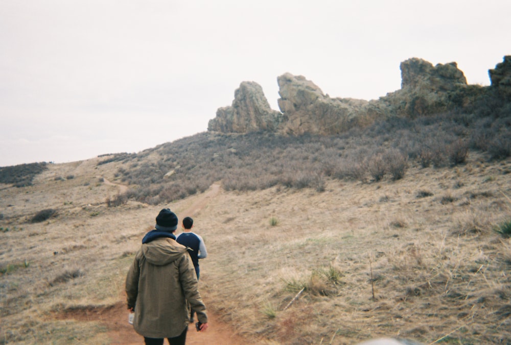 a couple of people walking down a dirt road