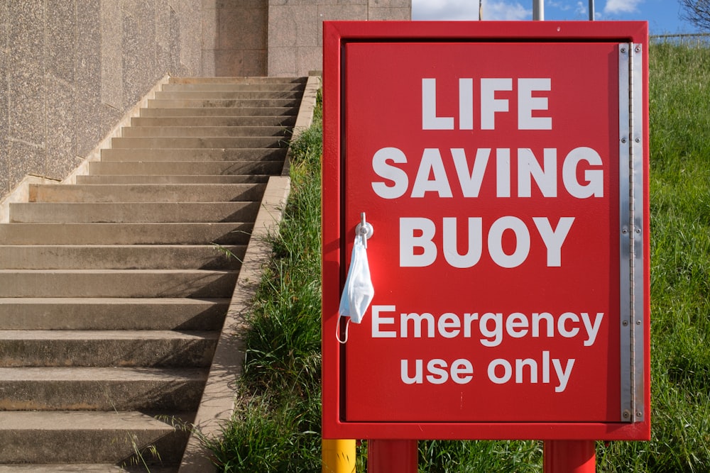 a red life saving buoy sign sitting on the side of a building