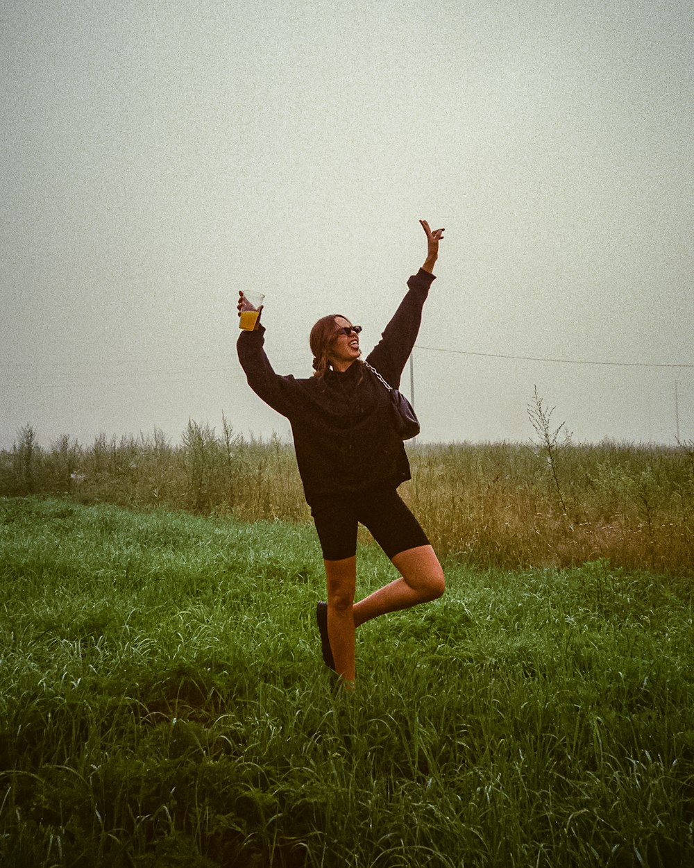a woman standing in a field with her arms in the air