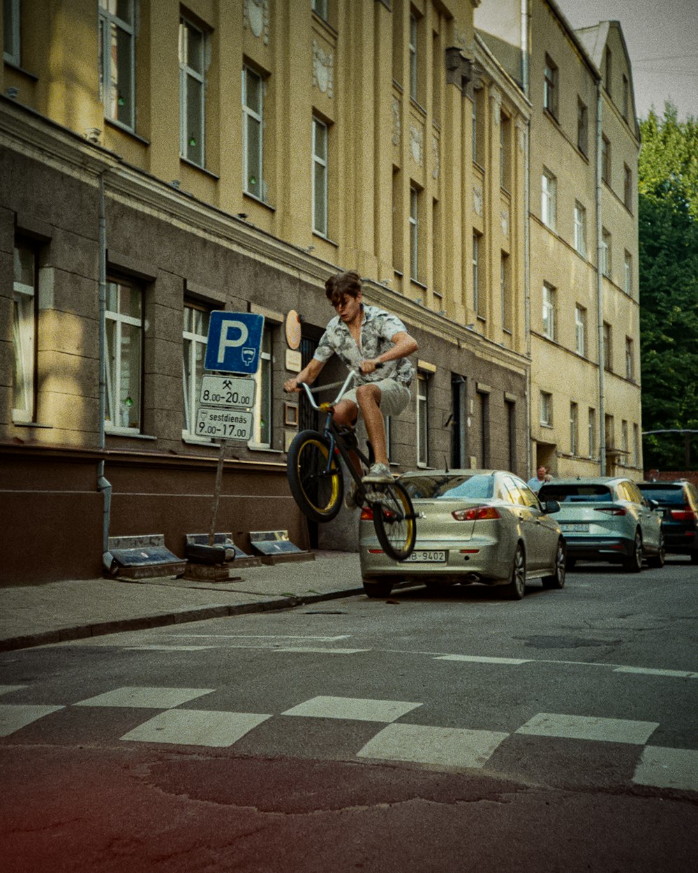 a man riding a bike down a street next to a car