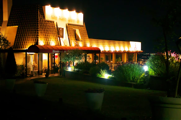 Elegant clubhouse exterior bathed in warm evening light with the golden beacon logo subtly glowing above the entrance.