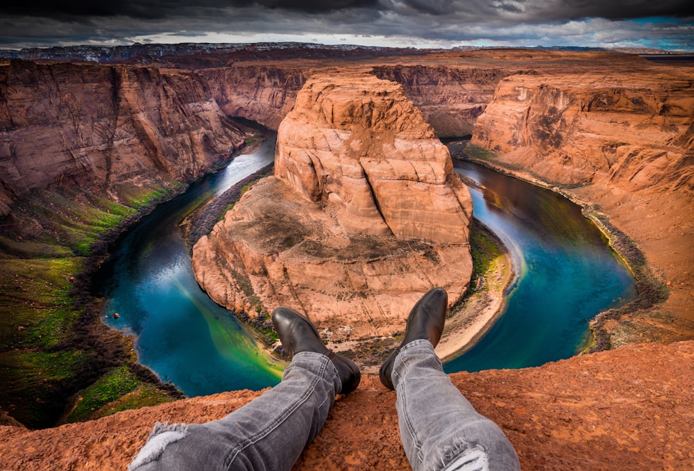 a person is sitting on a cliff overlooking a river